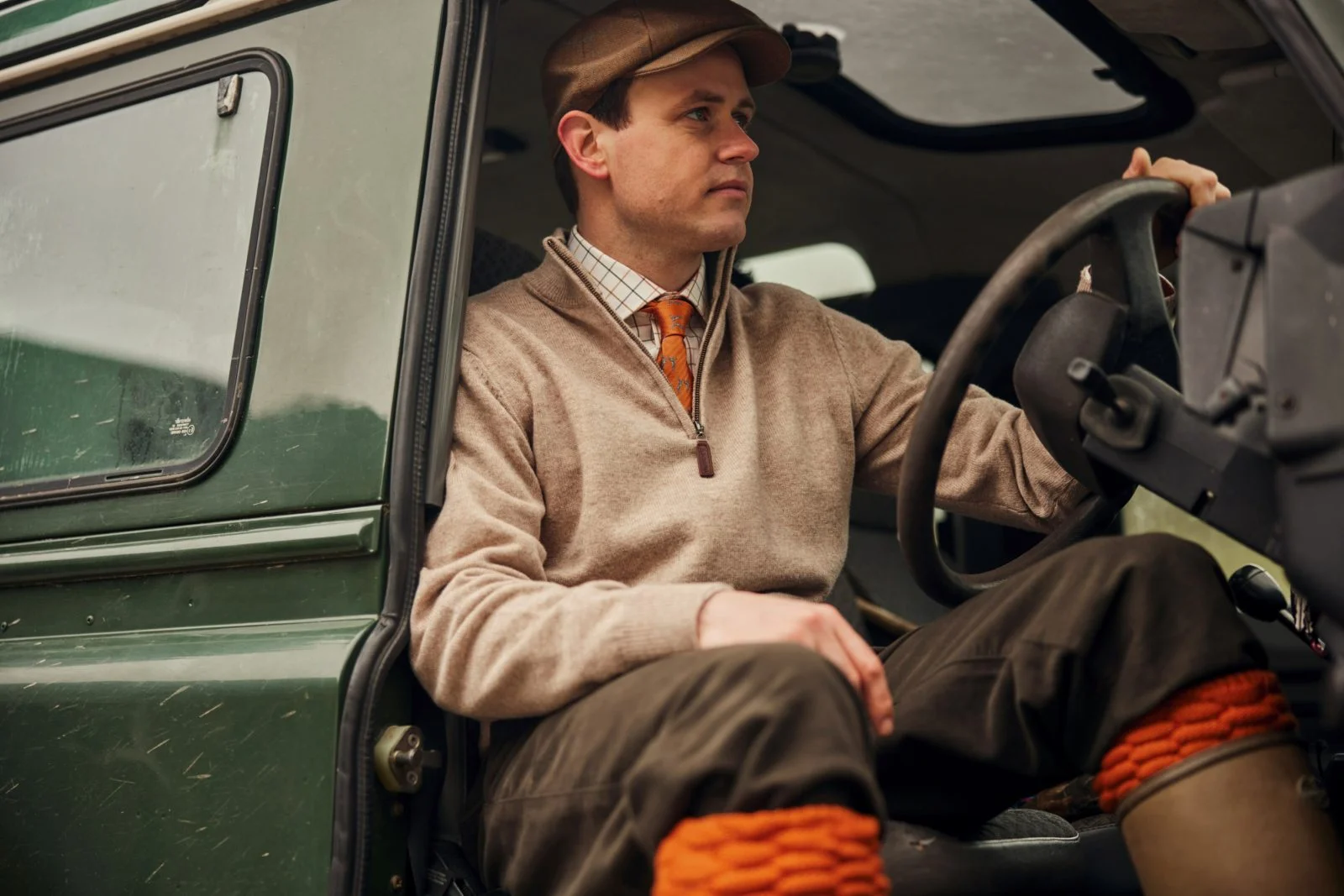 Gentleman sitting in a landrover wearing country clothing
